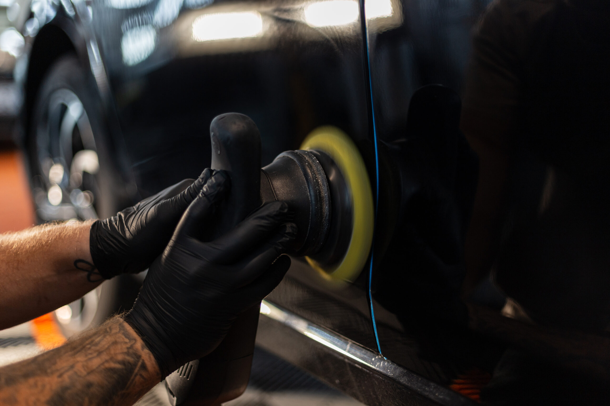 Professional man holding polishing machine Tools and polishing car in detailing studio. Car care