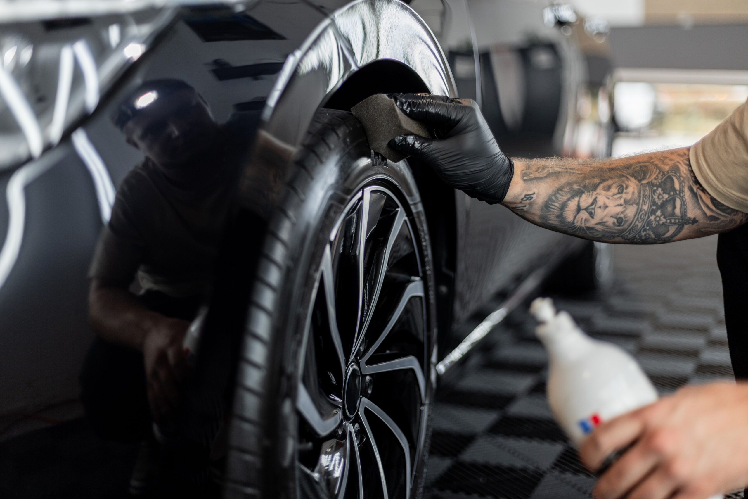 Professional man washing car and wheels in garage. Detailing. Tire care