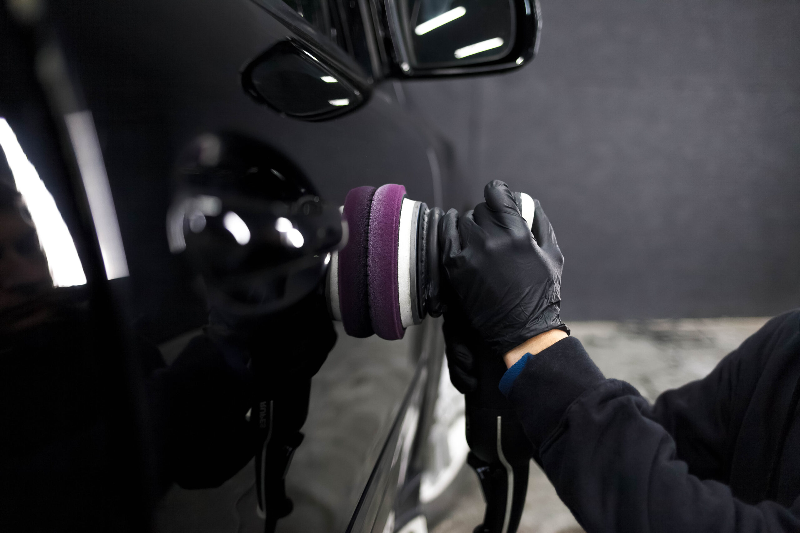 Worker of the detailing center polishes car body